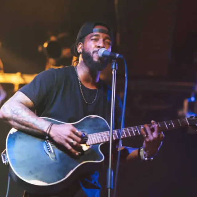Singer with an acoustic guitar performing at a microphone