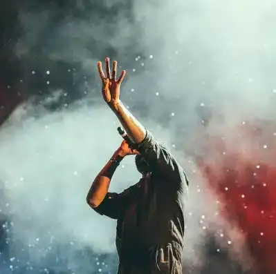 Singer with raised arms performing in stage smoke