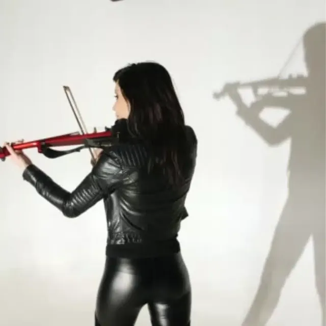 Electric violinist playing a red violin, her shadow on the wall behind her