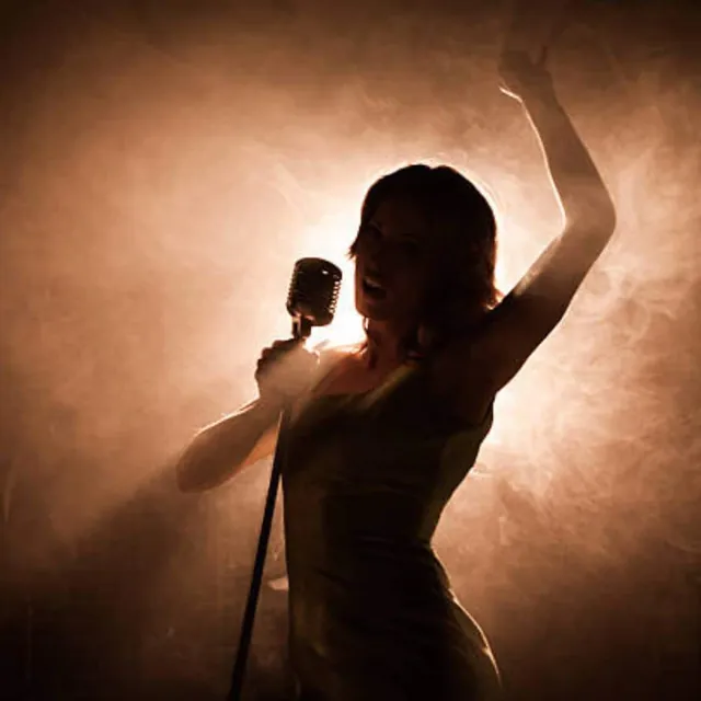 Female singer in silhouette, backlit by warm stage light