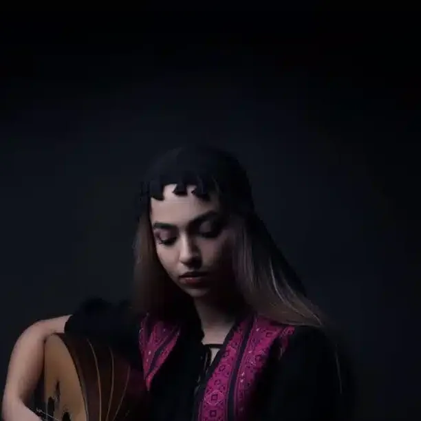 Female oud player in a dark embroidered dress, softly lit