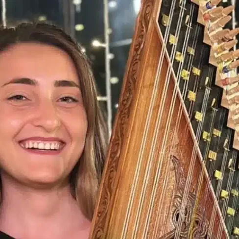 Smiling female qanun player holding an ornate qanun