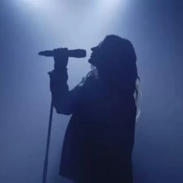 Female singer in silhouette at a microphone under blue light