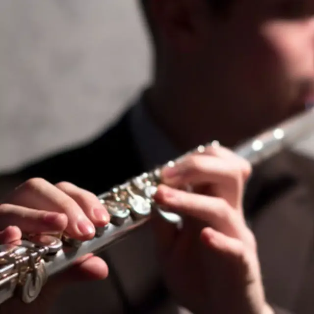 Close-up of hands playing a silver flute