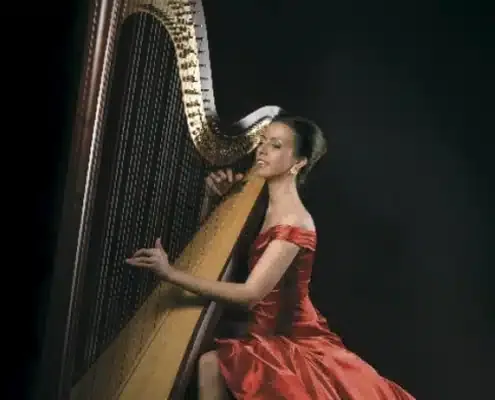 Harpist in a red gown playing a concert harp
