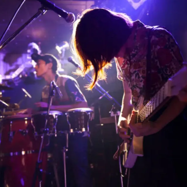 Latin band with congas, guitar and vocals on a purple-lit stage