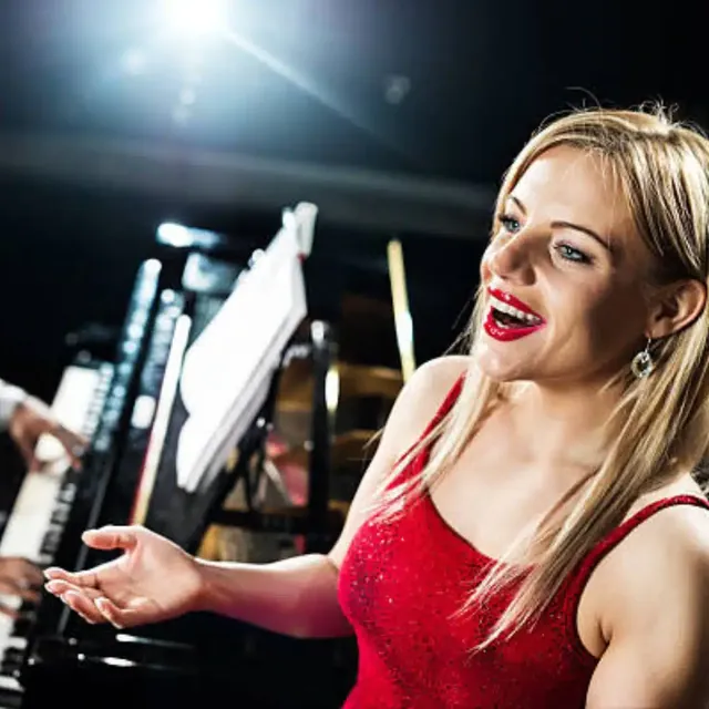 Opera singer in a red dress singing beside a pianist