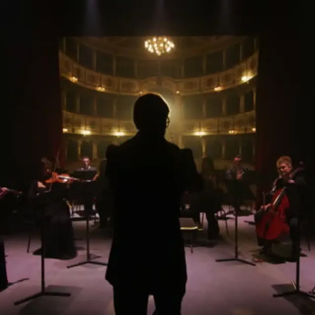 Conductor before a chamber orchestra on stage in an opera house