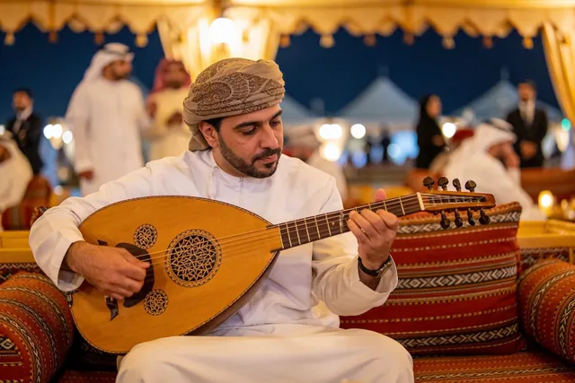 Oud player in a white kandura and turban performing in a majlis