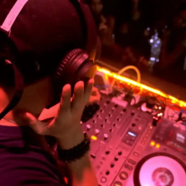 DJ in headphones at a mixer with pink lighting