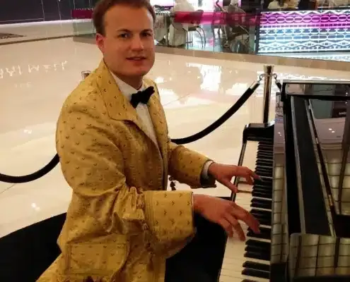 Pianist in a gold brocade jacket playing a grand piano in a mall atrium