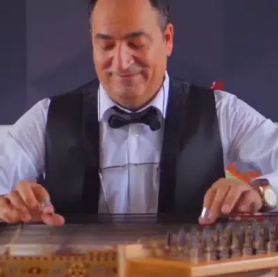 Qanun player in a bow tie and waistcoat playing the qanun