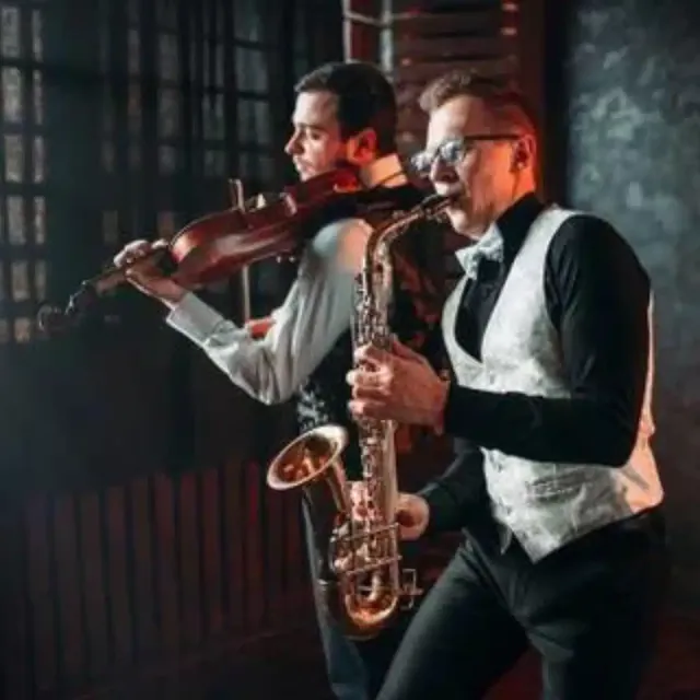 Violinist and saxophonist performing together in waistcoats