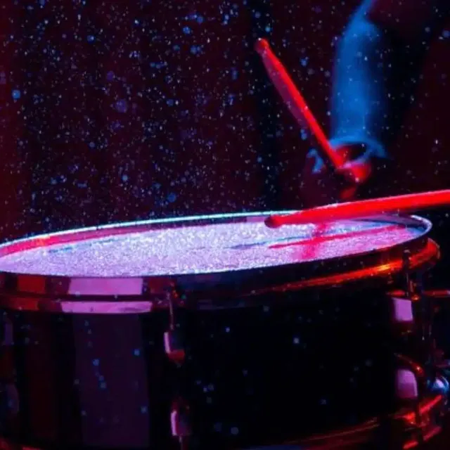 Drum surface splashing with water under red and blue light