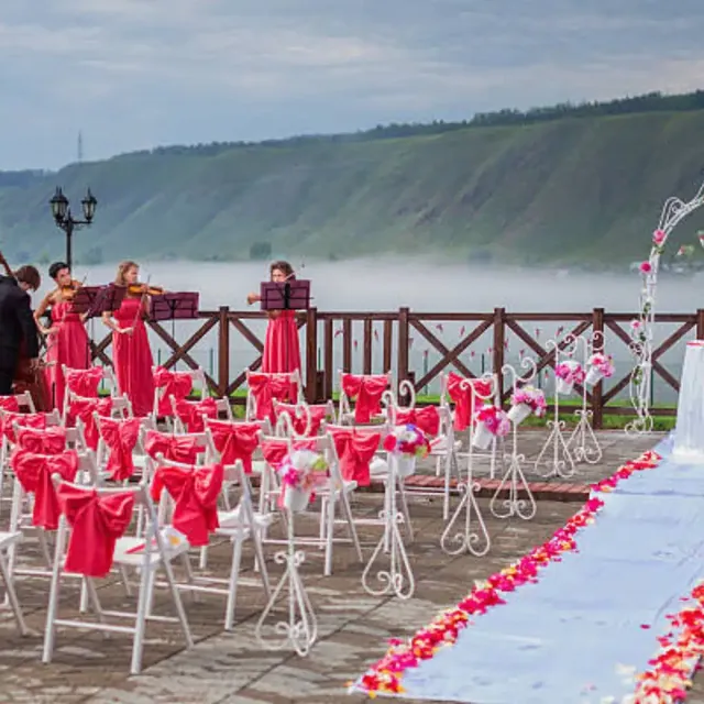 String players performing at an outdoor wedding ceremony by a lake